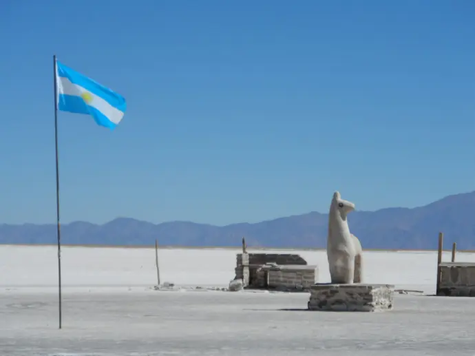 a flag and a statue in the middle of a desert