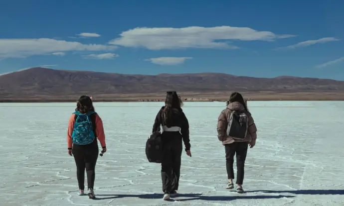 A group of three people walking across a snow covered field